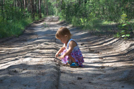 Baby girl on the field road playing in the forestの写真素材