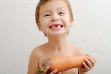 Happy cute boy edentate with carrot smilingの写真素材