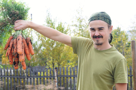 Happy agronome with bunch of fresh carrots