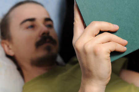 man reading literary book lying on coachの写真素材