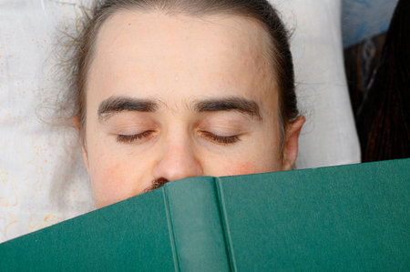 man student tired of reading book and sleeping