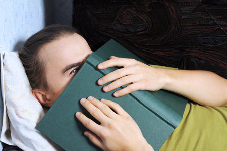 Young man peeping from behind the book