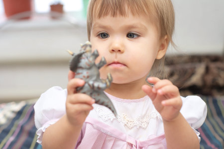 Little girl playing with dinosaur Triceratops toy