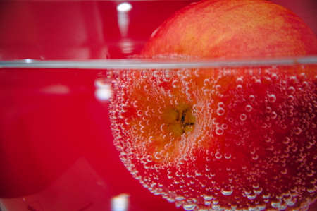 Red apple in the bubbles on red backgroundの写真素材