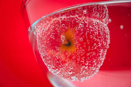 Red apple in the bubbles on red backgroundの写真素材