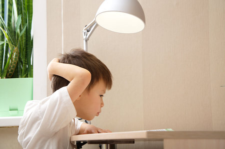 Boy holding his head while reading the book