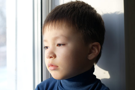 Boy portrait sitting on the window and thinking philosophical