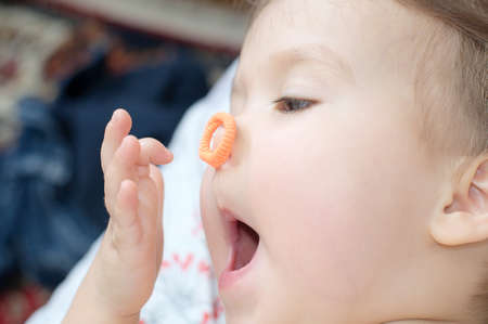Little baby girl having fun with elastic band on nouseの写真素材