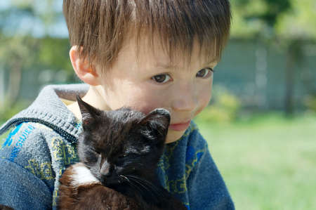 Boy with black kitten hugging with loveの写真素材