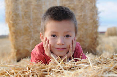 Boy portrait lying on the stack of hayの写真素材