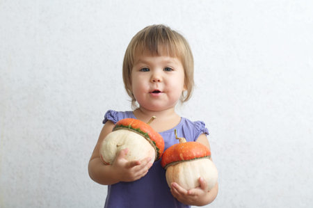 Little child girl holding two decorative pumpkinsの写真素材