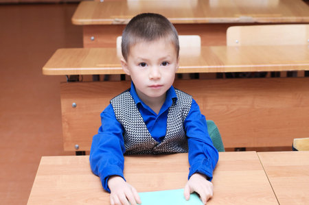 School boy portrait sitting in classroom with exercise bookの写真素材