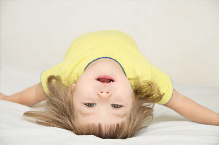 happy funny little girl arch her back lying on bed isolated, happy childhood concept