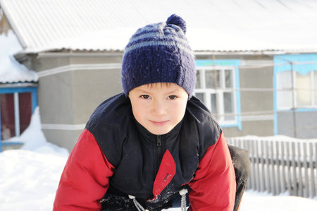 Winter activity - boy portrait at winter playing outdoor in warm clothesの写真素材
