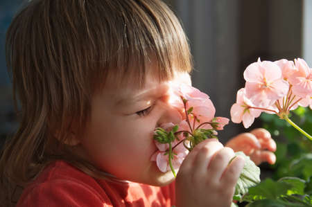 Little girl with funny face smelling spring flowers, kid funny face feeling happiness,joyful people concept without spring allergyの写真素材