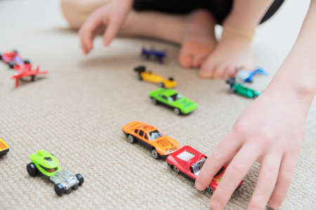 boy playing with car collection on carpet.Child hand play. Transportation, airplane, plane and helicopter toys for children, miniature models. Many cars for little boys.の写真素材