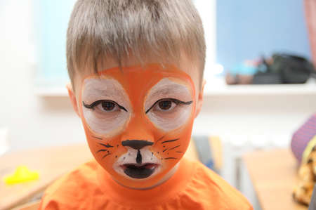 Make up artist making tiger mask for child.Children face painting. Boy  painted as tiger or ferocious lion. Preparing for theatrical performance. Boy actor playing role. Tiger mask faceの写真素材