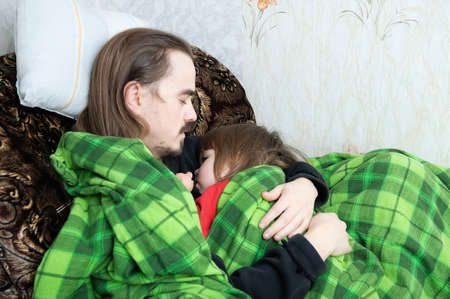 Father and daughter sleeping together on armchair. Family resting. Happy parenthood, fatherhood. Dad and daughter wrapped in blanket sleep quite.の写真素材