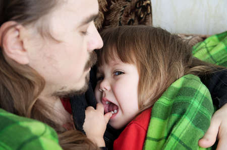 Father and child resting together on armchair. Family concept. Happy parenthood, fatherhood. Dad and daughter wrapped in blanket sweetの写真素材