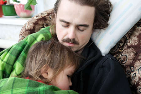Father and kid sleeping together home on armchair. Family resting. Happy parenthood, fatherhood. Dad and daughter wrapped in blanket sleep quite.の写真素材