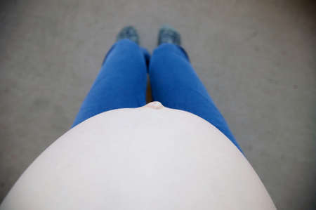 Pregnant belly of sitting woman relaxing selfie view from above. Expecting baby birth in third trimester for being mother. Prenatal period, pregnancy health, prepared for child birth concept. New lifeの写真素材