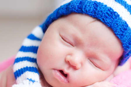 Cute newborn baby in blue striped knitted cap sleeping. Infant sleeping portrait.の写真素材