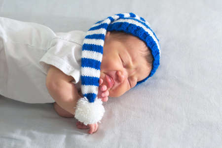 newborn in hat on white blanket, asian baby stomach ache.
Infant care, teething pain, colic ache conceptの写真素材
