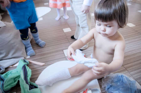 Child wearing clothes in kindergarden, white socks in kids handsの写真素材