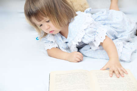 Little toddler girl refusing to read book and to learn looking unhappyの写真素材