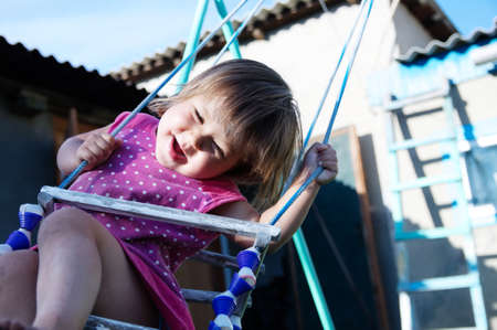 Funny little girl swing outdoor at summer, child playing activityの写真素材