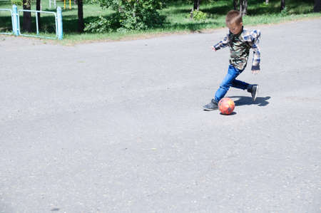Boy playing football, child run with ball on asphalt, soccer team player, training outdoor, active lifestyle, sport backgroundの写真素材