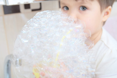 Cute little girl playing with soap bubbles in the bathroom