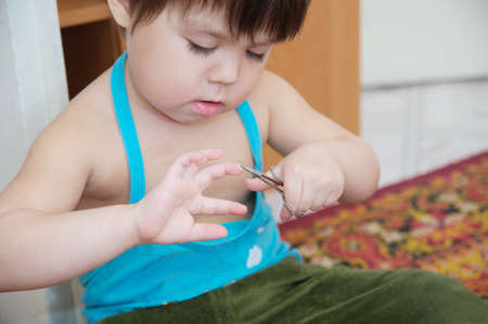 Little girl cutting fingernails herself working with scissors learning self maintenanceの写真素材