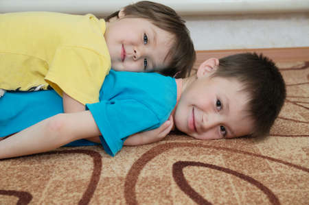 Happy smiling children lying on each other like stairs. Siblings - boy and little girl - together playing. family portrait with different age kids. Domestic games.  Childhood in complete full familyの写真素材