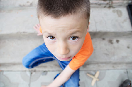 top view boy portrait close-up sitting on stairs. Child face. Caucasian kid. fisheye effect....