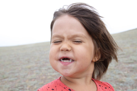happy funny girl with expression portrait. Wind is blowing. Smiling without teeth little child....