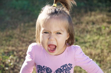 Little girl portrait outdoor screaming grasping defending her opinionの写真素材