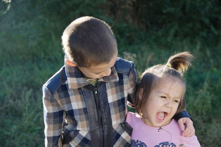 Boy and funny little girl hugging portrait. Happy smiling children outdoors at sunny day. Friendship siblings. Brother embrace little sisterの写真素材