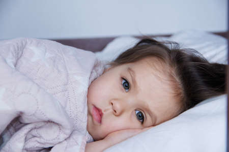 little girls going to sleep lying on bed. sleep schedule in domestic lifestyle. cute baby child portraitの写真素材