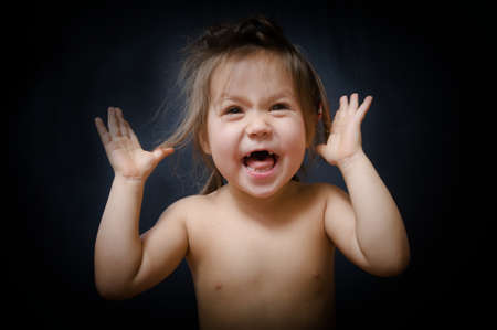 Child wondering emotionally on dark background. little girl surprising and saying something amazingの写真素材