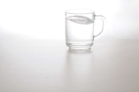 Water wave in transparent glass and puddle on gray background. purified fresh drink water on tableの写真素材