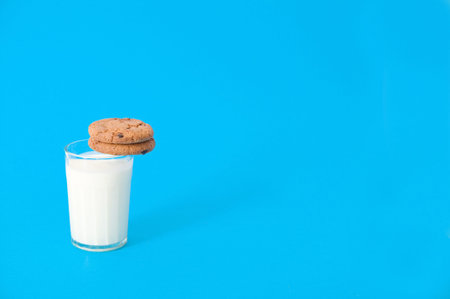 glass of milk and cookies on blue background. oatmeal cookie with pieces of chocolate