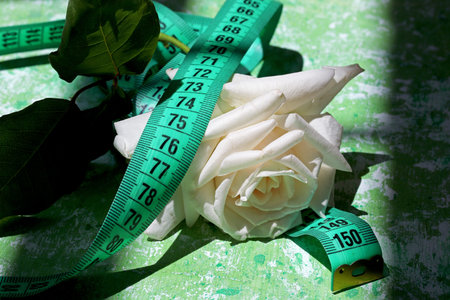 diet concept with measuring tape and white rose