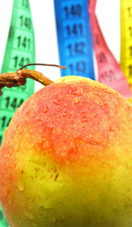 diet concept with measuring tape and a pear in the background