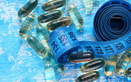 pills and measuring tape on blue backgroundの写真素材
