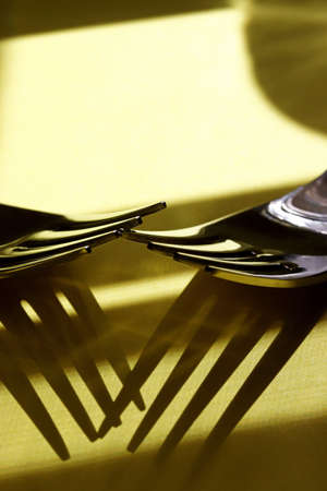 close-up metal fork with shadows on yellow backgroundの写真素材