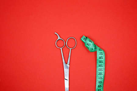green tape measure and scissors on red backgroundの写真素材