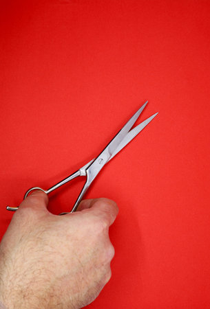 hand holding scissors on red background