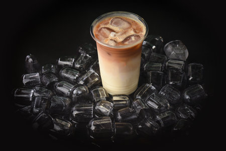Iced coffee in plastic cup with ice cubes on black background.の写真素材