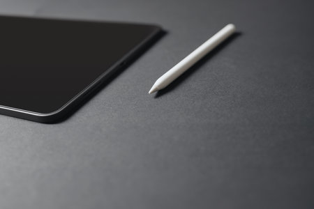 Black tablet with white pencil on black background. Close-up.の写真素材